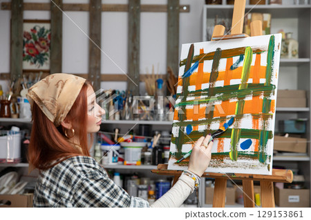 A Creative Young Artist is Engaged in Painting within a Bright and Inspiring Studio Environment 129153861