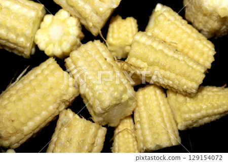 Close up of baby sweetcorn chopped on black background Close up of baby sweetcorn chopped on black background 129154072