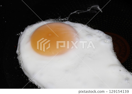 Fresh egg frying in a pan with golden yolk 129154139