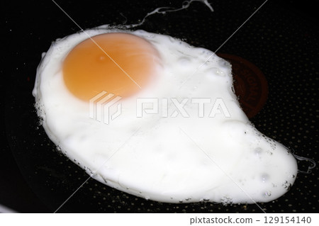 Fresh egg frying in a pan with golden yolk 129154140