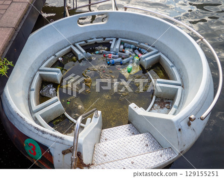 Half-submerged pleasure boat. Dirt and plastic bottles in the water. Ecological catastrophy. Environmental problems. Garbage in the water. Half-submerged pleasure boat. Dirt and plastic bottles in the water. Ecological catastrophy. Environmental problems. Garbage in the water. 129155251