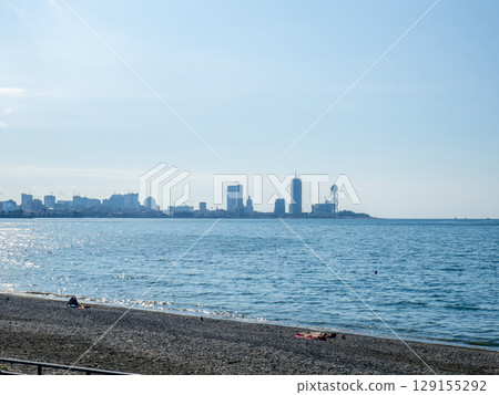Sea coast against the backdrop of the city. Few people on the beach. Rocky shore of the Black Sea. Seaside holiday concept. Batumi. 129155292