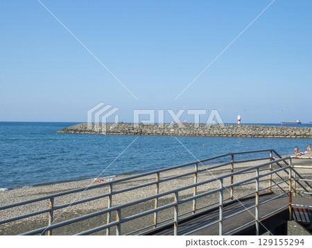 Sea coast against the backdrop of the city. Few people on the beach. Rocky shore of the Black Sea. Seaside holiday concept. Batumi. 129155294
