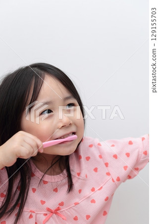 4-year-old girl in pajamas brushing her teeth 4-year-old girl in pajamas brushing her teeth 129155703
