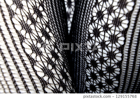 Close up of black lace fishnet tights on skin legs curves abstract background 129155768