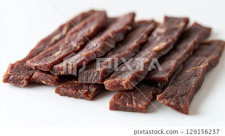 Thin slices of jerky, showing a rich, dark texture with visible marbling 129156237
