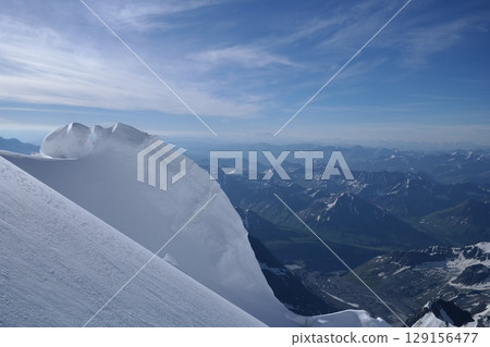 Tranquil Lake With Lush Green Forest, Snow-Capped Mountain, Blue Sky And White Clouds Tranquil Lake With Lush Green Forest, Snow-Capped Mountain, Blue Sky And White Clouds 129156477