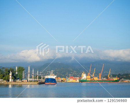 Landscape in the seaport. Port in the Caucasus. Ships and mountains. Clouds over the mountains. Port in Batumi. Logistics. Black Sea cargo transportation industry 129156980