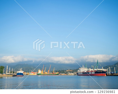Landscape in the seaport. Port in the Caucasus. Ships and mountains. Clouds over the mountains. Port in Batumi. Logistics. Black Sea cargo transportation industry 129156981