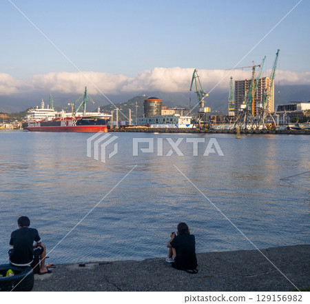 Landscape in the seaport. Port in the Caucasus. Ships and mountains. Clouds over the mountains. Port in Batumi. Logistics. Black Sea cargo transportation industry Landscape in the seaport. Port in the Caucasus. Ships and mountains. Clouds over the mountains. Port in Batumi. Logistics. Black Sea cargo transportation industry 129156982
