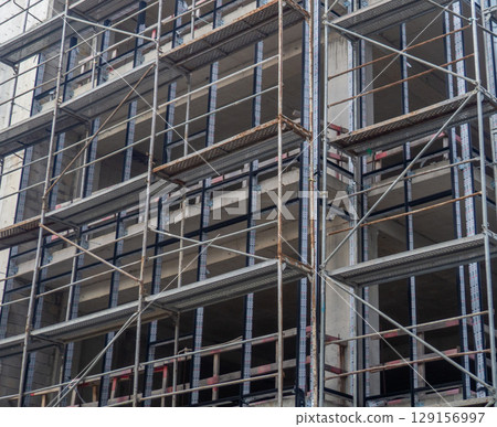 Construction of a concrete house. Modern buildings. Scaffolding. 129156997