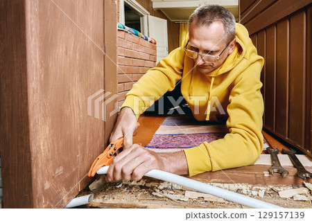 Plumber trims plastic pipe using cutting tool to ensure proper connection surface for placing compression ring and mounting threaded fitting. 129157139