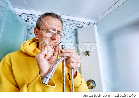 Replacing sealing ring on braided shower hose, plumber inserts new gasket into connector while standing inside shower stall during repair process. 129157140