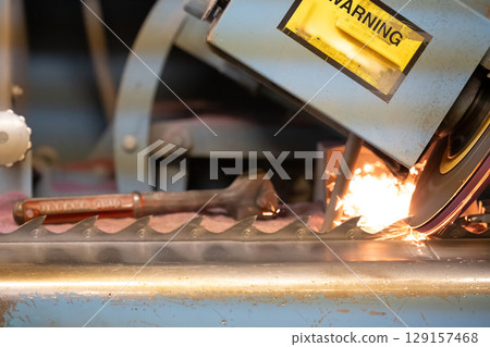 Sparks fly during metalworking process in industrial workshop in daylight 129157468