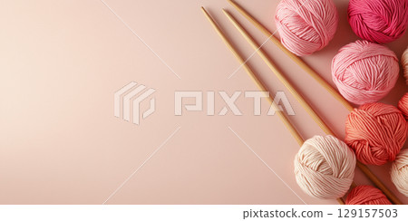 Delicate banner with space for text for knitting related topics and yarn shops, pink balls of yarn and wooden knitting needles on light background 129157503