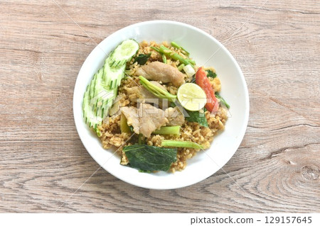 fried rice solf fermenting pork in black sweet soy sauce with slice cucumber couple lemon on plate  129157645