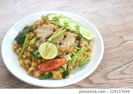 fried rice solf fermenting pork in black sweet soy sauce with slice cucumber couple lemon on plate  129157646
