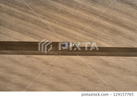 plowing farm after harvesting with vehicle 129157765
