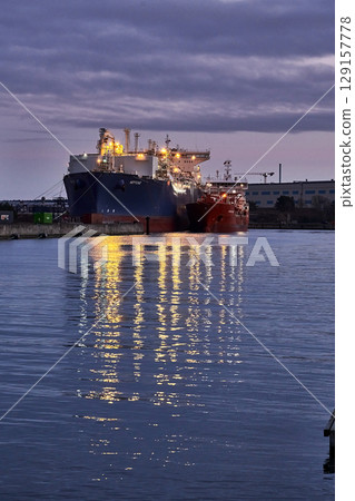 Lubmin, Germany - 01 28 2023: First LNG terminal with LNG tanker Neptune (Offshore Support Vessel, IMO 9385673) moored for regasification of LNG from LNG tanker Coral Furcata in the evening Lubmin, Germany - 01 28 2023: First LNG terminal with LNG tanker Neptune (Offshore Support Vessel, IMO 9385673) moored for regasification of LNG from LNG tanker Coral Furcata in the evening 129157778