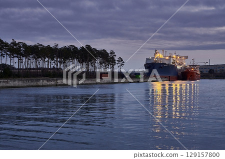 Lubmin, Germany - 01 28 2023: First LNG terminal with LNG tanker Neptune (Offshore Support Vessel, IMO 9385673) moored for regasification of LNG from LNG tanker Coral Furcata in the evening Lubmin, Germany - 01 28 2023: First LNG terminal with LNG tanker Neptune (Offshore Support Vessel, IMO 9385673) moored for regasification of LNG from LNG tanker Coral Furcata in the evening 129157800