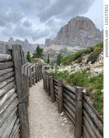 Historic World War I trench in the Italian Dolomites, surrounded by alpine peaks. A symbol of wartime history set against natural beauty. Historic and travel concept Historic World War I trench in the Italian Dolomites, surrounded by alpine peaks. A symbol of wartime history set against natural beauty. Historic and travel concept 129157852