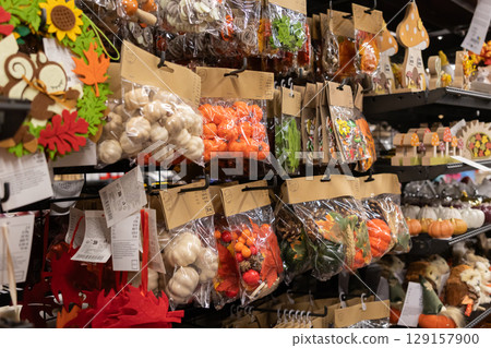 Various autumn decorative items, including pumpkins, leaves, and berries, packaged for sale on a retail shelf, symbolizing seasonal home decor Various autumn decorative items, including pumpkins, leaves, and berries, packaged for sale on a retail shelf, symbolizing seasonal home decor 129157900