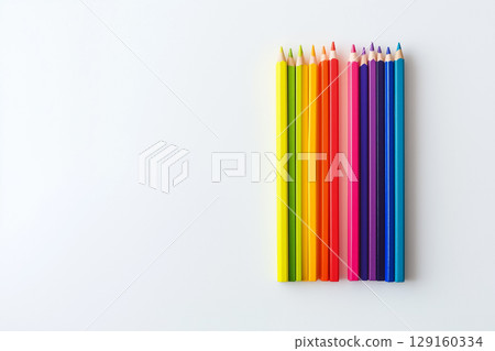 A set of rainbow-colored pencils arranged in a circular pattern on a clean white surface 129160334