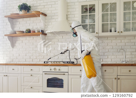 Service man disinfecting kitchen in client house or doing pest control with disinfectant spray. Service man disinfecting kitchen in client house or doing pest control with disinfectant spray. 129160792