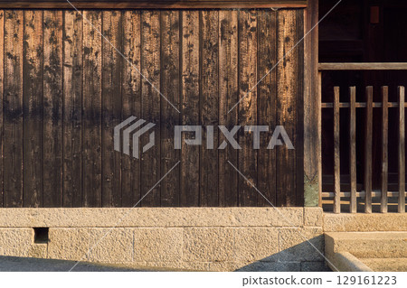 日本傳統建築的背景資料。燒焦的杉木牆板、石砌地基和格子屏風。 日本傳統建築的背景資料。燒焦的杉木牆板、石砌地基和格子屏風。 129161223
