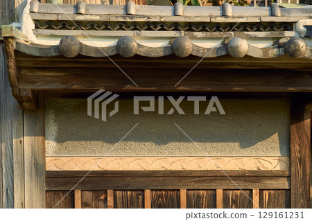 傳統日式房屋的外觀。背景材料。瓦屋頂、土牆和燒製的杉木板牆。 傳統日式房屋的外觀。背景材料。瓦屋頂、土牆和燒製的杉木板牆。 129161231