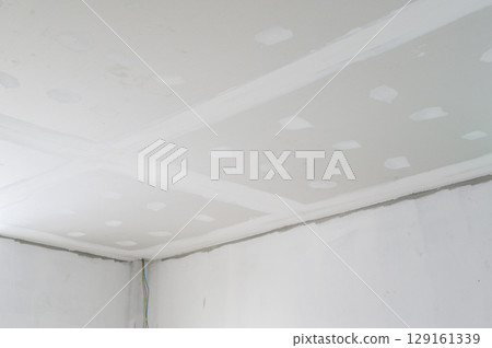 Interior building renovation underway. Gypsum board ceiling installed. Smooth plastering finish applied to smooth edges. Electrical wire present. New ceilings improve space, se building progress 129161339