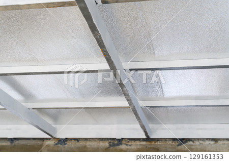 Metal framework supports sheet of pu foam insulation. Construction material forms an interior ceiling surface showing visible beams structure and panel texture. foam insulation provides energy Metal framework supports sheet of pu foam insulation. Construction material forms an interior ceiling surface showing visible beams structure and panel texture. foam insulation provides energy 129161353