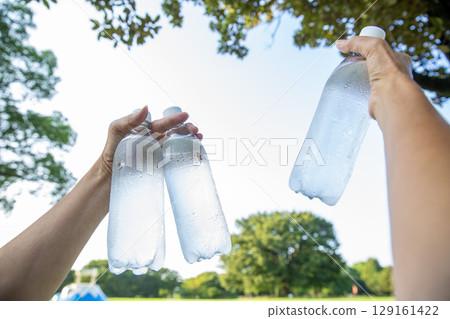 Cold water in a plastic bottle in hand, mineral water, hot summer Cold water in a plastic bottle in hand, mineral water, hot summer 129161422