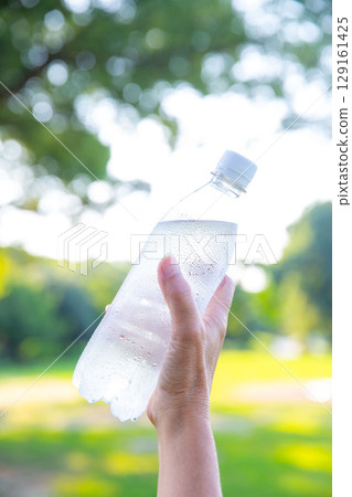 Cold water in a plastic bottle in hand, mineral water, hot summer Cold water in a plastic bottle in hand, mineral water, hot summer 129161425