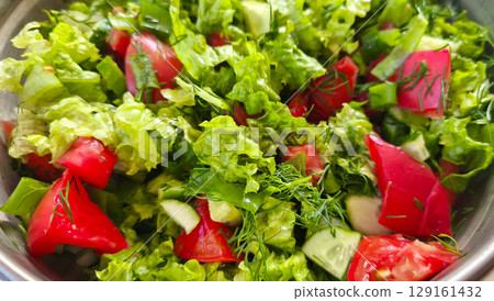 Close-up of green salad with lettuce, dill, tomatoes and cucumbers. Spring summer salad of fresh vegetables. Diet healthy food.  129161432