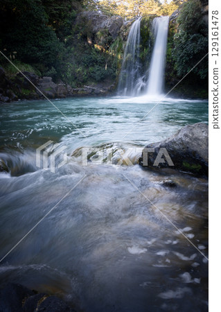 Vertical shot of beautiful cascade waterfall in a dense forest, New Zealand Vertical shot of beautiful cascade waterfall in a dense forest, New Zealand 129161478