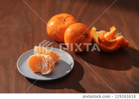 Peeled tangerines on a walnut wood table 129161618