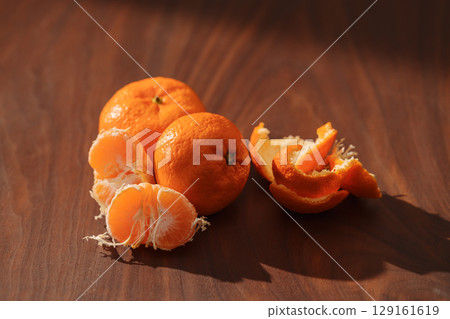 Peeled tangerines on a walnut wood table 129161619