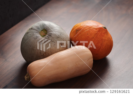 Different pumkins on walnut wood table 129161621