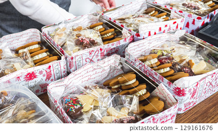 Lovingly homemade gingerbread and sugar cookies, half-dipped in rich chocolate, nestled in decorative Christmas tin boxes perfect for seasonal gifting. 129161676