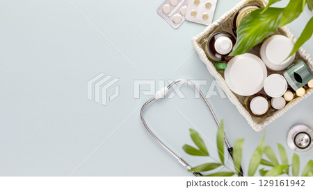 Set of medications with a stethoscope on a blue background with green leaves and copy space. Concept of medicine, healthcare and medication treatment. First aid kit, medicine box. Flat lay 129161942