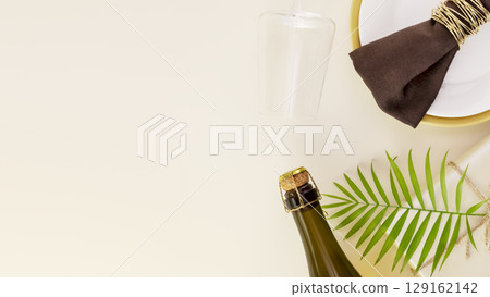 Holiday table setting. Present with palm leaf, bottle of champagne and glass on a beige background with copy space. Rosh hashanah, Jewish New Year holiday. Flat lay 129162142