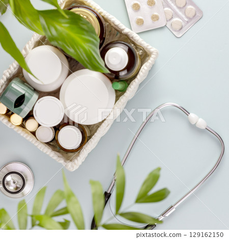 Set of medications with a stethoscope on a blue background with home plante. Concept of medicine, healthcare and medication treatment. first aid kit, medicine box. Flat lay 129162150