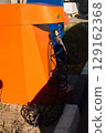 Vibrant orange air pump station for tire inflation with a pressure gauge and black hose 129162368