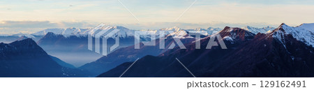 Misty Mountain Valley with Snow-Capped Peaks at Dusk near Piani di Bobbio in Italy Misty Mountain Valley with Snow-Capped Peaks at Dusk near Piani di Bobbio in Italy 129162491