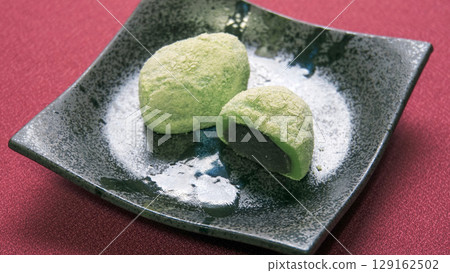 Uguisu mochi, served on a black plate, evokes the arrival of spring Uguisu mochi, served on a black plate, evokes the arrival of spring 129162502