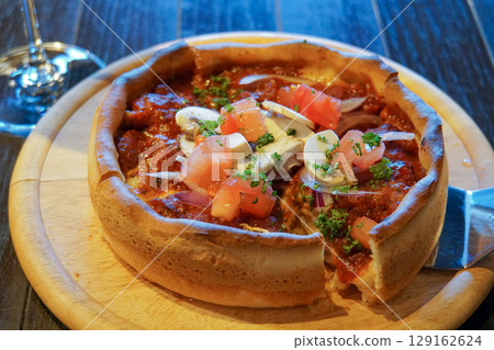 A sliced Chicago pizza with a thick crust and plenty of toppings 129162624