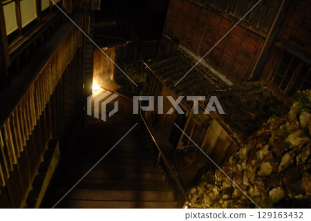 Warm lights and wooden houses decorate the cobblestone streets at night 129163432