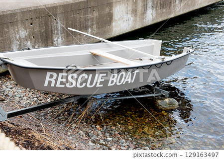 Rescue boat stationed on rocky shoreline near harbor Rescue boat stationed on rocky shoreline near harbor 129163497
