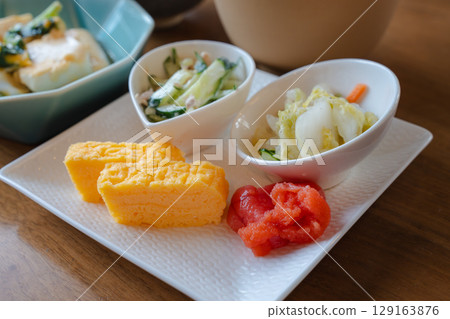 A Japanese breakfast set featuring stir-fried tofu and vegetables and tamagoyaki (rolled egg) A Japanese breakfast set featuring stir-fried tofu and vegetables and tamagoyaki (rolled egg) 129163876